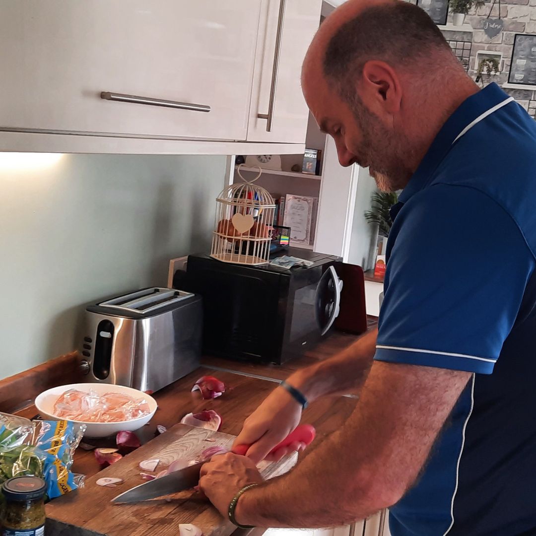 Marco prepares fresh ingredients in his home kitchen. Here, he is slicing an onion.