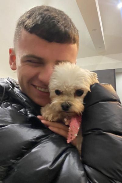 Photo shows Caolan, 18, cuddling a white dog.