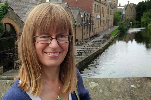 Annette Henry stands smiling at the camera on a bridge over a canal.