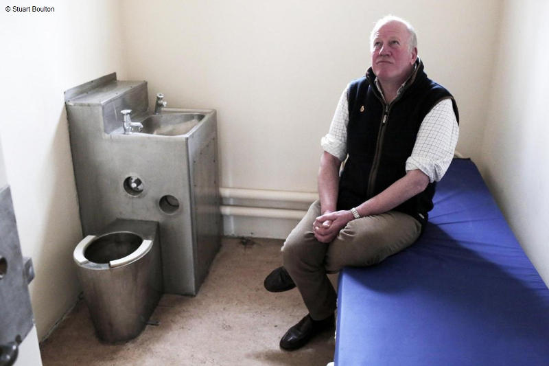 Simon sits in his cell