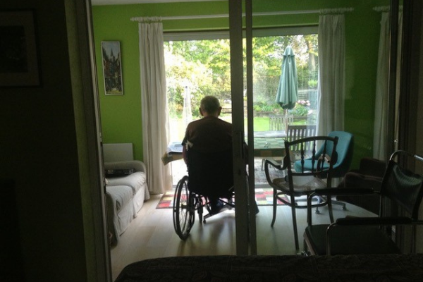 Terry Oliver sits in his wheelchair looking out at the garden outside.