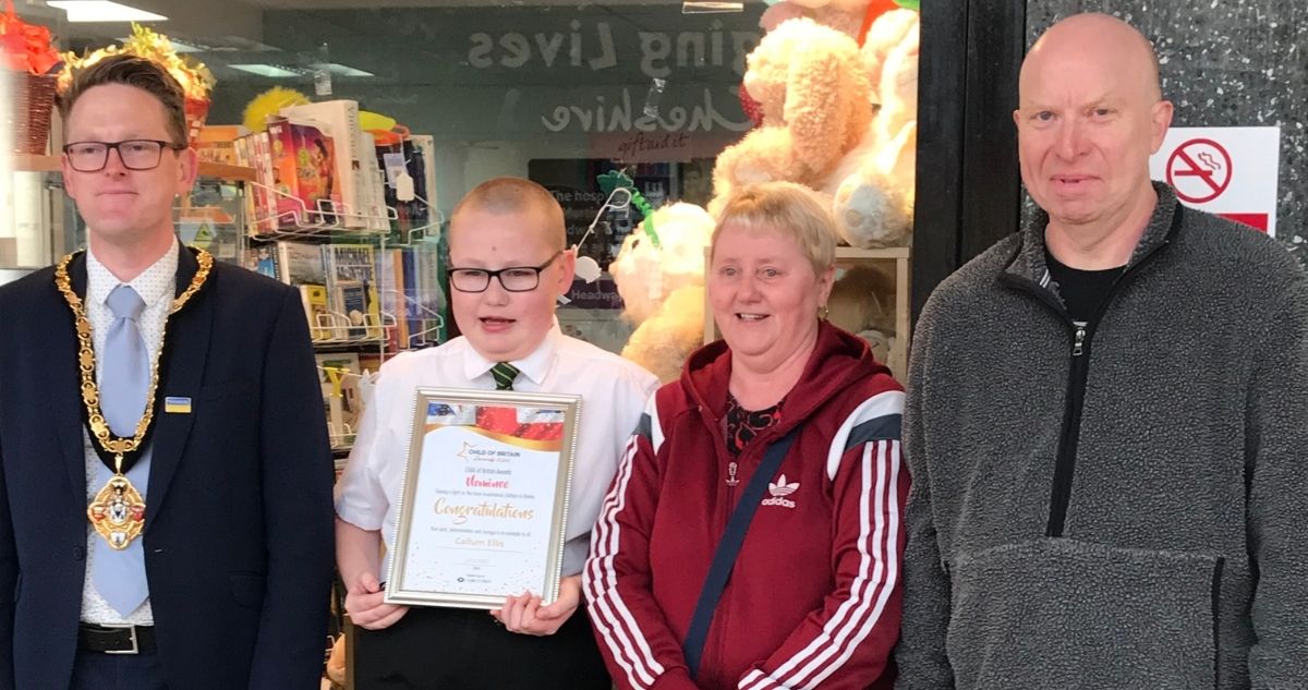Callum (second from left) receives his award certificate outside Headway's charity shop in Winsford